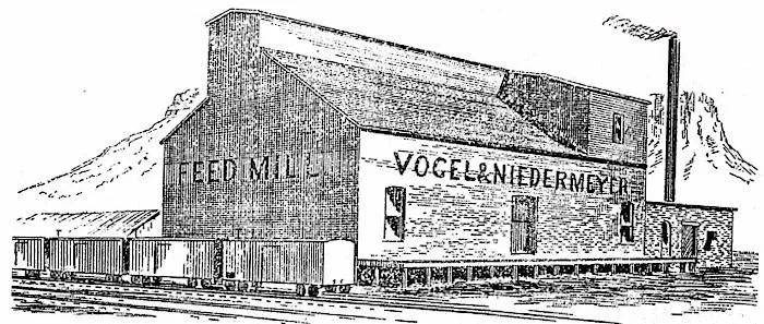 2 story building with FEED MILL sign, freight cars parked alongside