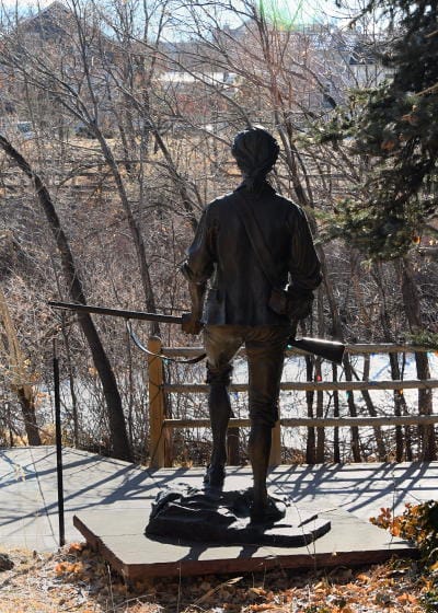 Statue of a Minuteman with musket overlooking Clear Creek in Golden