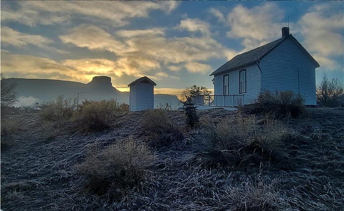 Guy Hill Schoolhouse and its outhouse with Castle Rock in the background