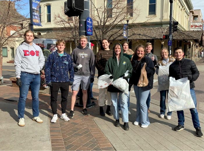 Ten college students--many holding plastic trash bags--standing at 12th and Washington in downtown Golden