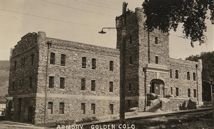 The Armory building in downtown Golden, Colorado: constructed of river rock, the building is three stories tall with a tower on the west side that rises to a fourth story.