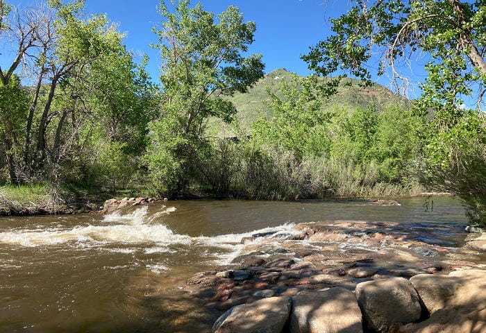 Clear Creek running high, spilling over rocks, with Mount Zion in the background