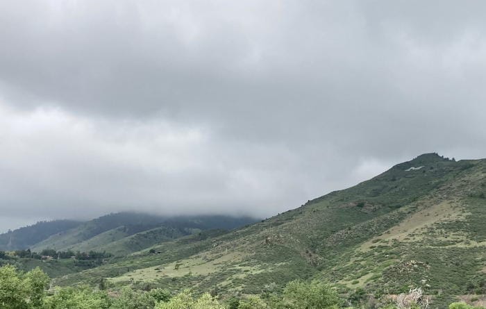 Low-hanging clouds obscuring the top of Lookout Mountain west of Golden, CO. Mount Zion, with its School of Mines M-blem, is fully visible.