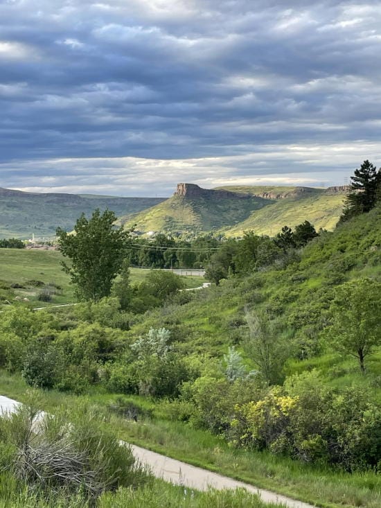 South Table Mountain in the distance with deep green foliage in the foreground and heavy cloud cover overhead