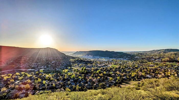 View across the Golden valley with the sun low in the eastern sky.  Both Table Mountains appear in the distance and houses fill the mid-ground.