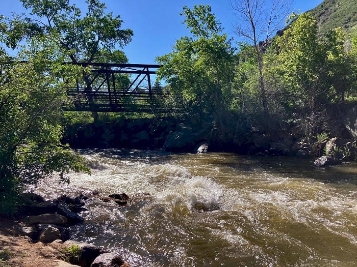 Color photo showing turbulent water in Clear Creek - pedestrian bridge over the Creek