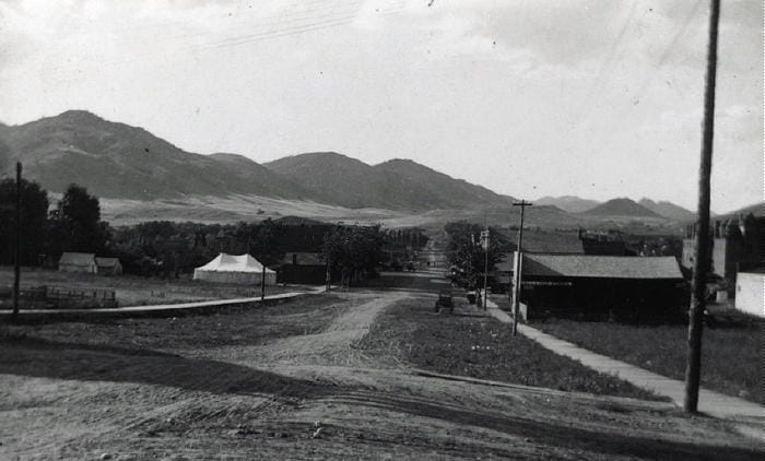 Black and white photo of Washington Avenue before it was paved  A large tent is set up in a vacant lot at approximately 13th and Washington.