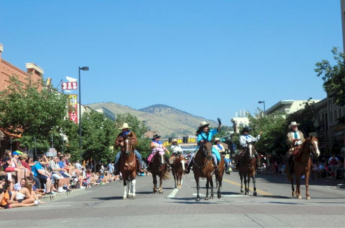 A line of horses with riders stretch across Washington Avenue in the Buffalo Bill Days parade