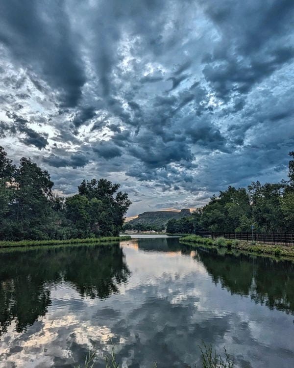 Dark, dramatic blue-gray clouds over the pond and Castle Rock