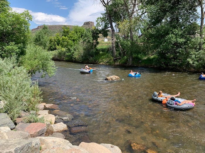 Tubers and rafters floating down Clear Creek.  Castle Rock in the background.