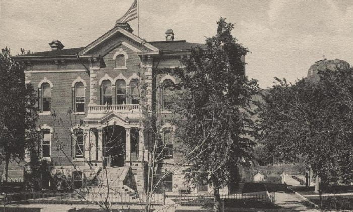 black and white postcard view of the 1878 courthouse with Castle Rock in the background