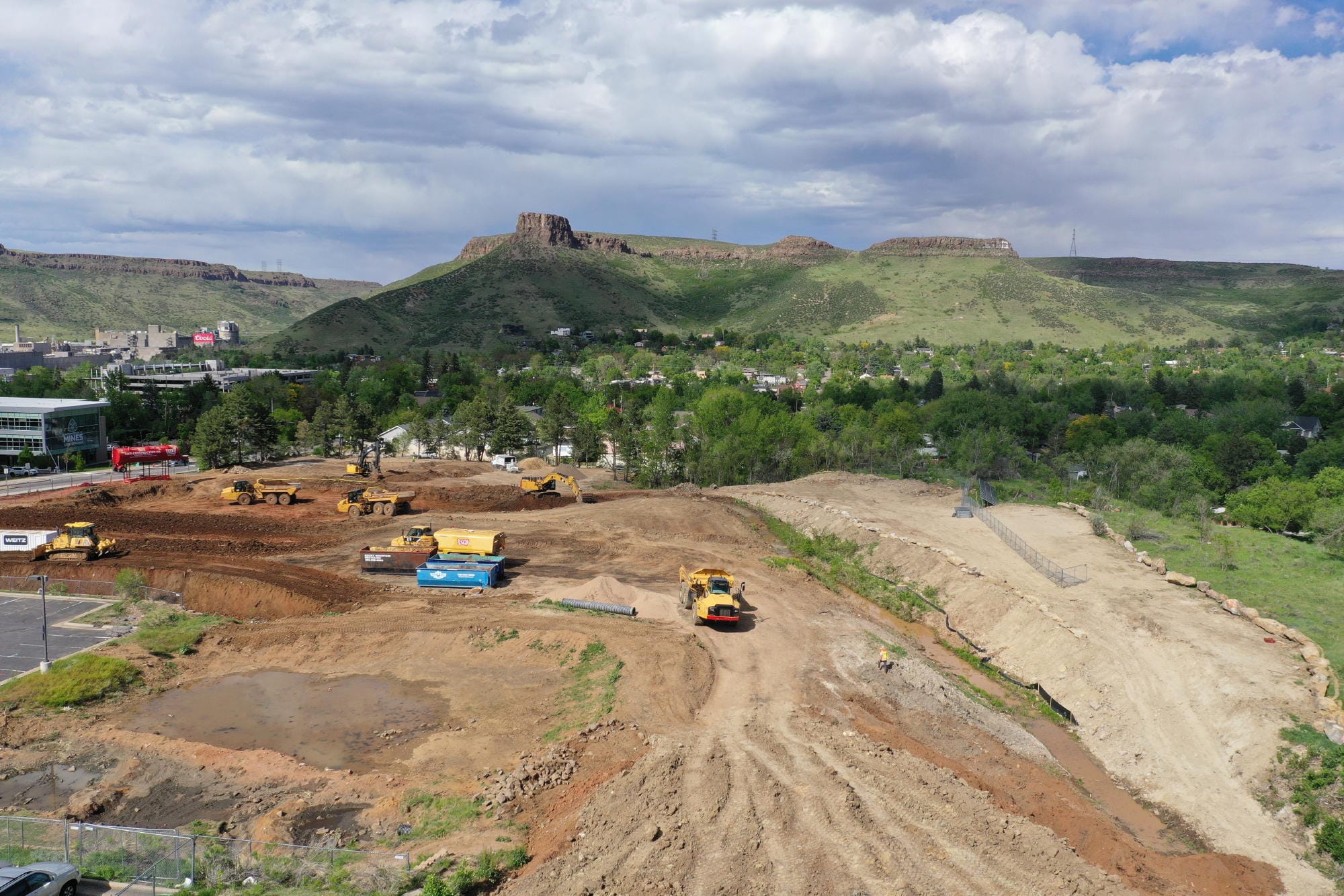 bulldozers grading the site, exposing reddish soil