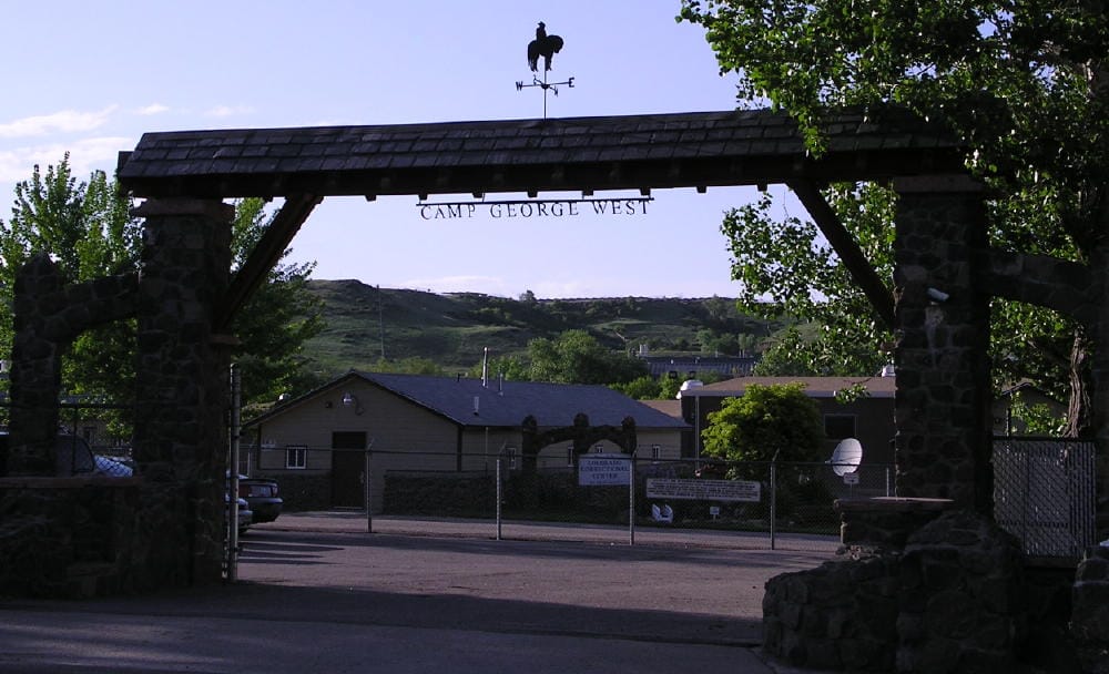 stone gateway with the words "CAMP GEORGE WEST" hanging from the cross piece