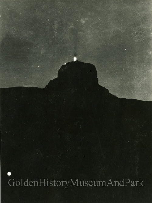 silhouette of Castle rock with something (a cross) burning at the top