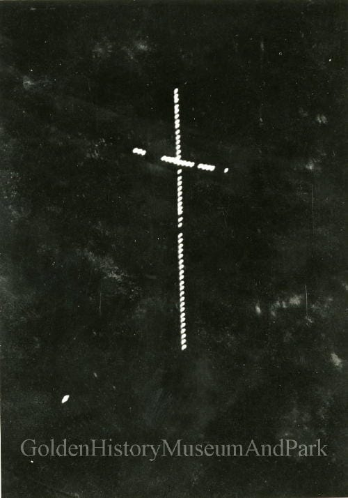 night photo showing electric light bulbs mounted on a cross