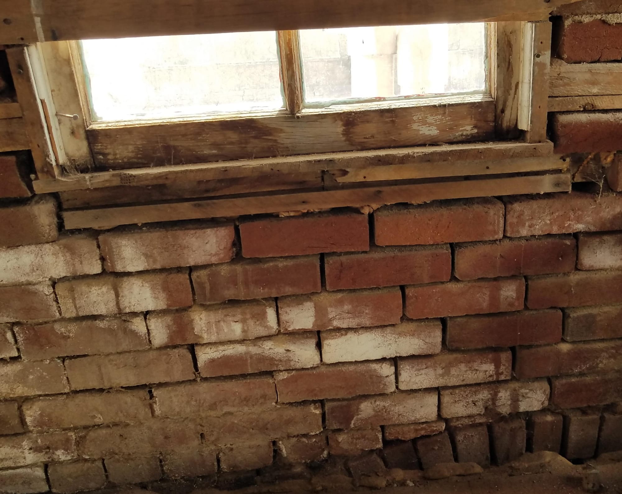 brick walls with little mortar visible; water damaged wood sill under window