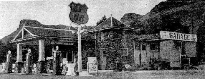 Phillips 66 station with three gas pumps and a portico in front, Castle Rock in the background