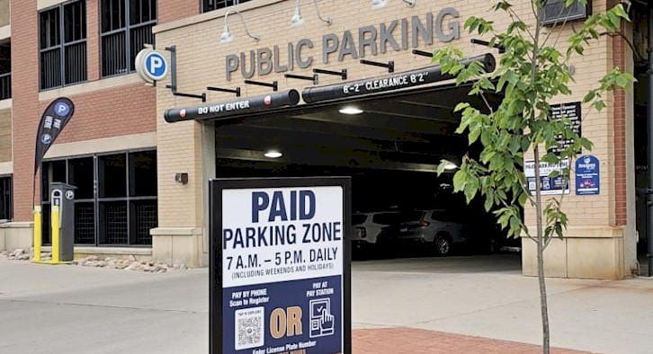 public parking garage with "Paid Parking Zone" sign and a "Pay Here" kiosk