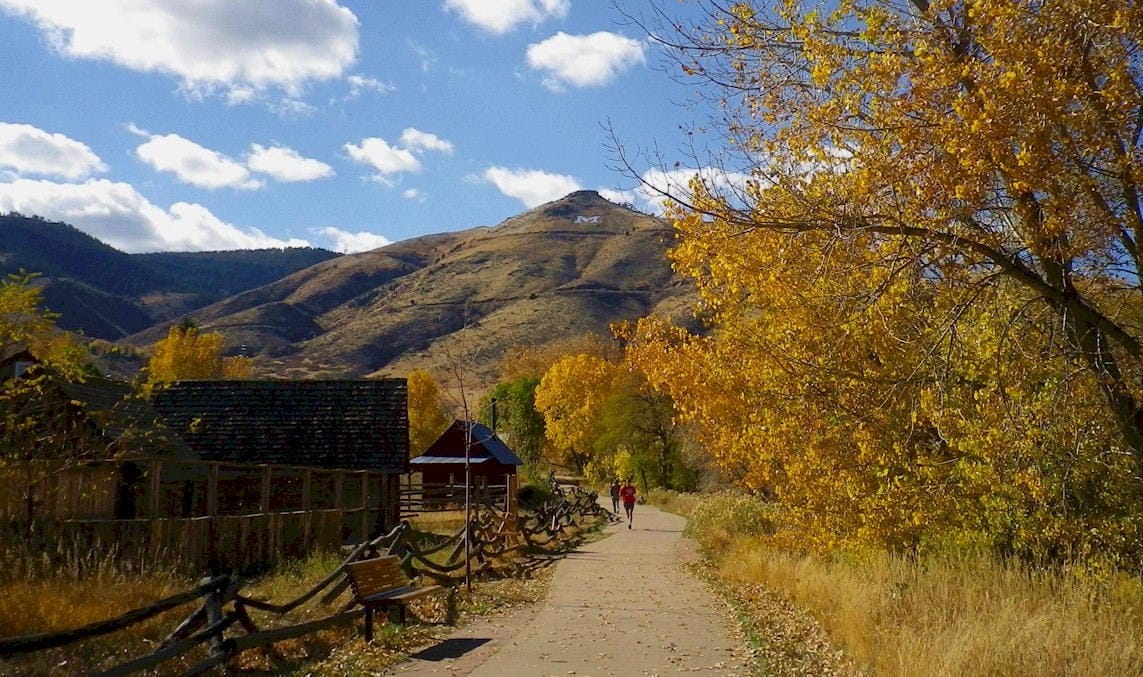 a runner on the trail next the history park on a bright fall day with golden foliage