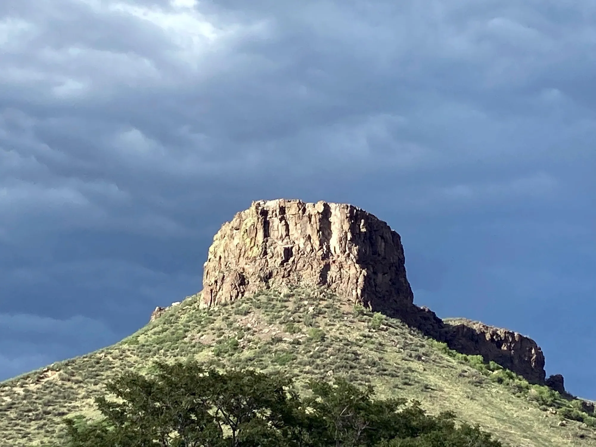 shows the South Table Mountain rock formation called Castle Rock.  Storm clouds in the background.