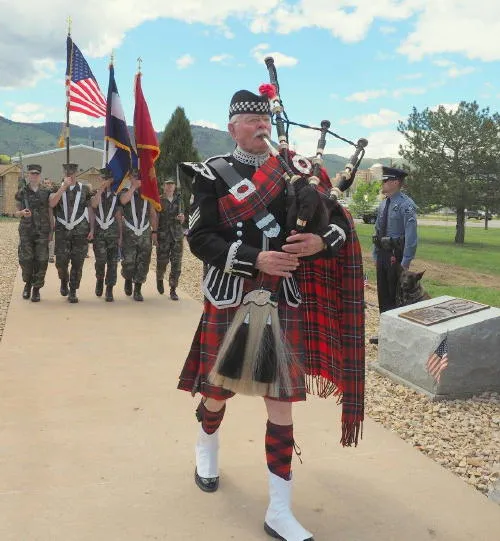 bagpiper in kilt followed by color guard carrying American, Colorado, and Marine Corps flags