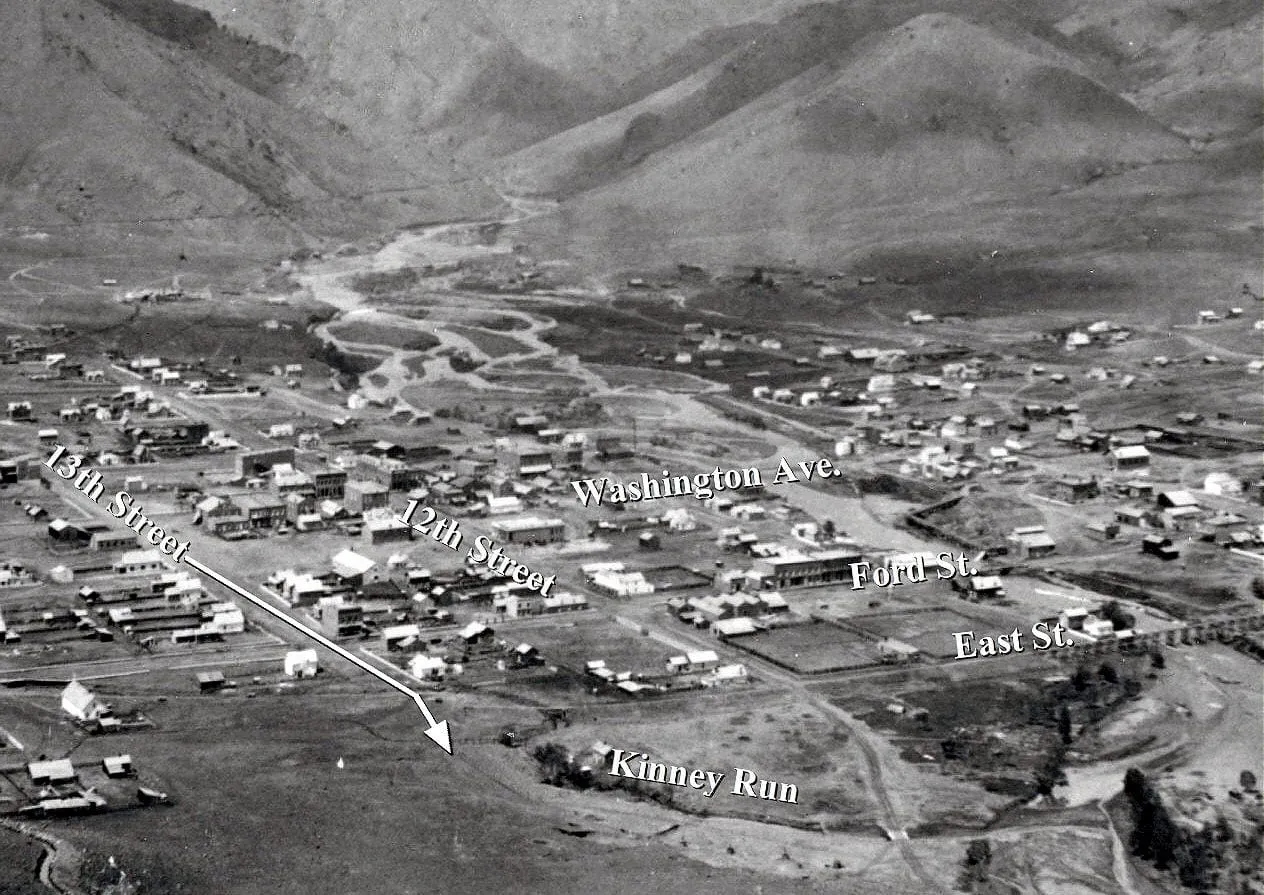 early photo of Golden showing dirt street, frame houses, and a  very wide channel for Clear Creek
