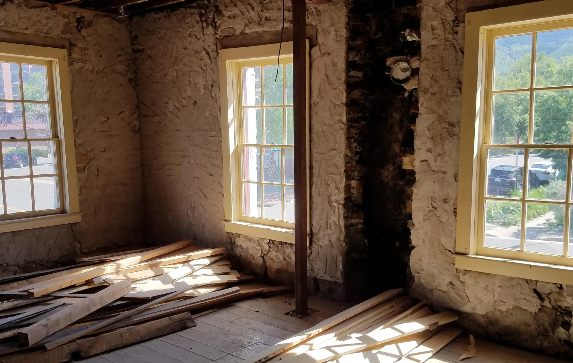 sun streaming through casement windows - lumber on the floors, stone walls