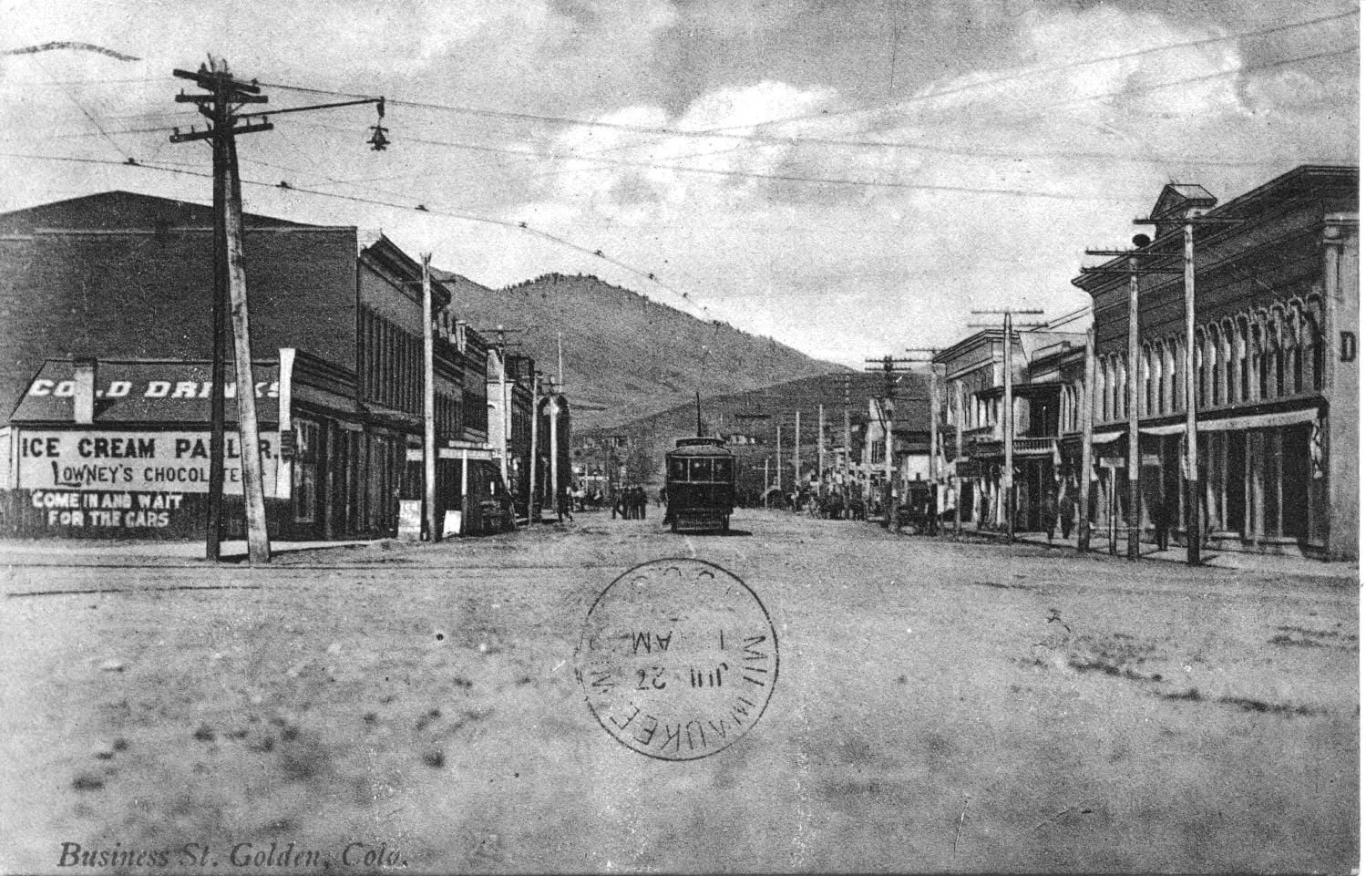 Washington Avenue, still a dirt street, with a streetcar coming down the center - utility wires overhead