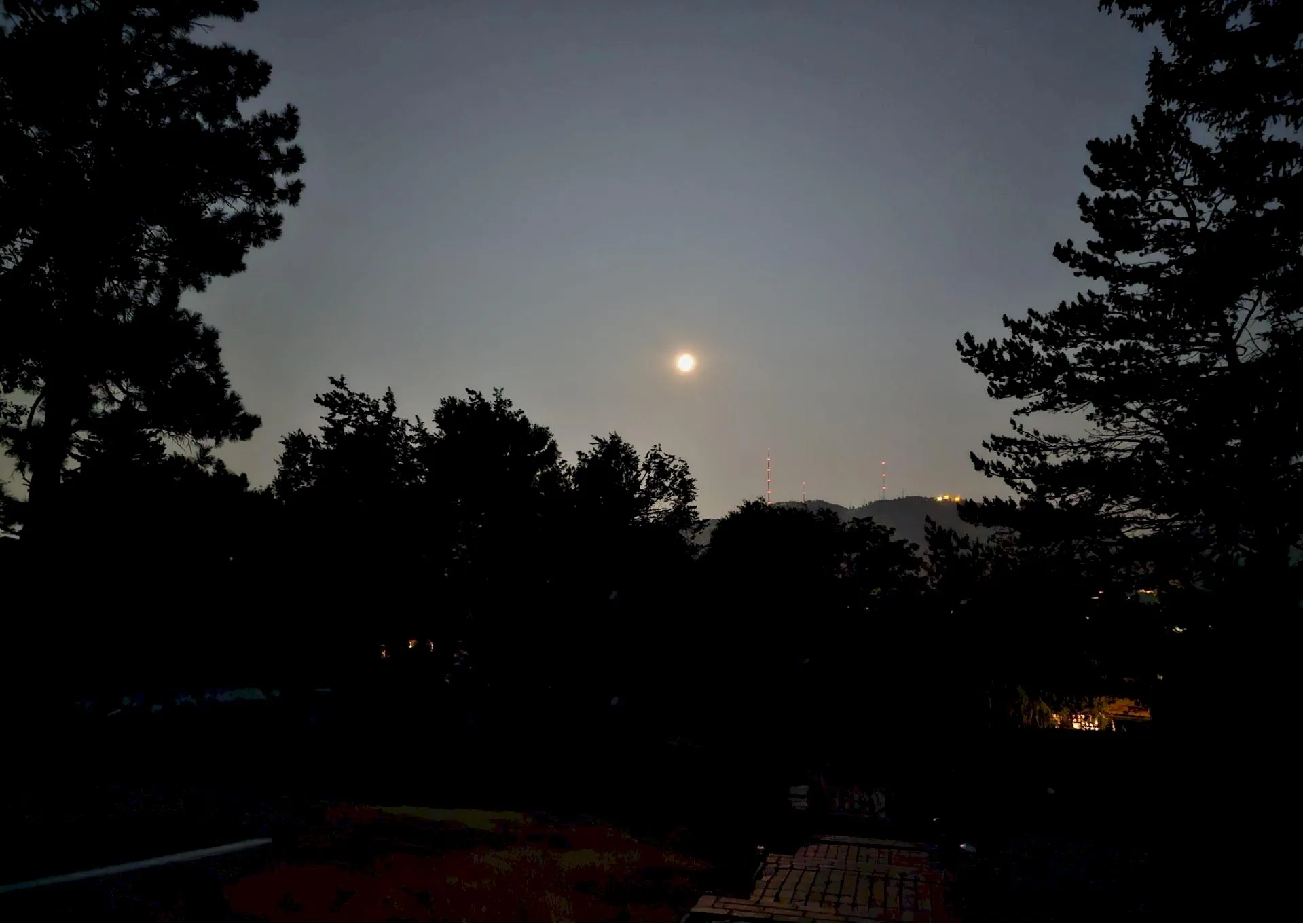 orange, hazy moon setting over the red-lighted antennas on Lookout Mountain