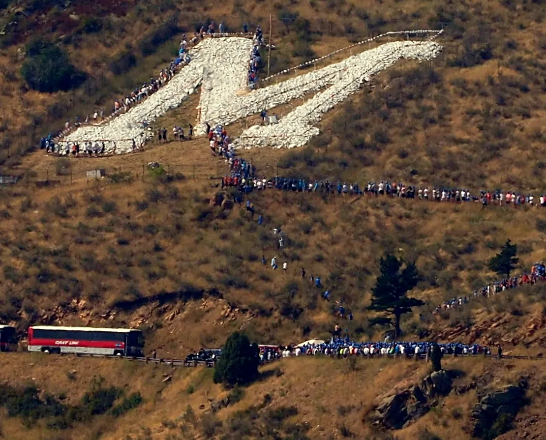 close-up of the M on Mt Zion with lies of people hiking up to it - bus parked on the road