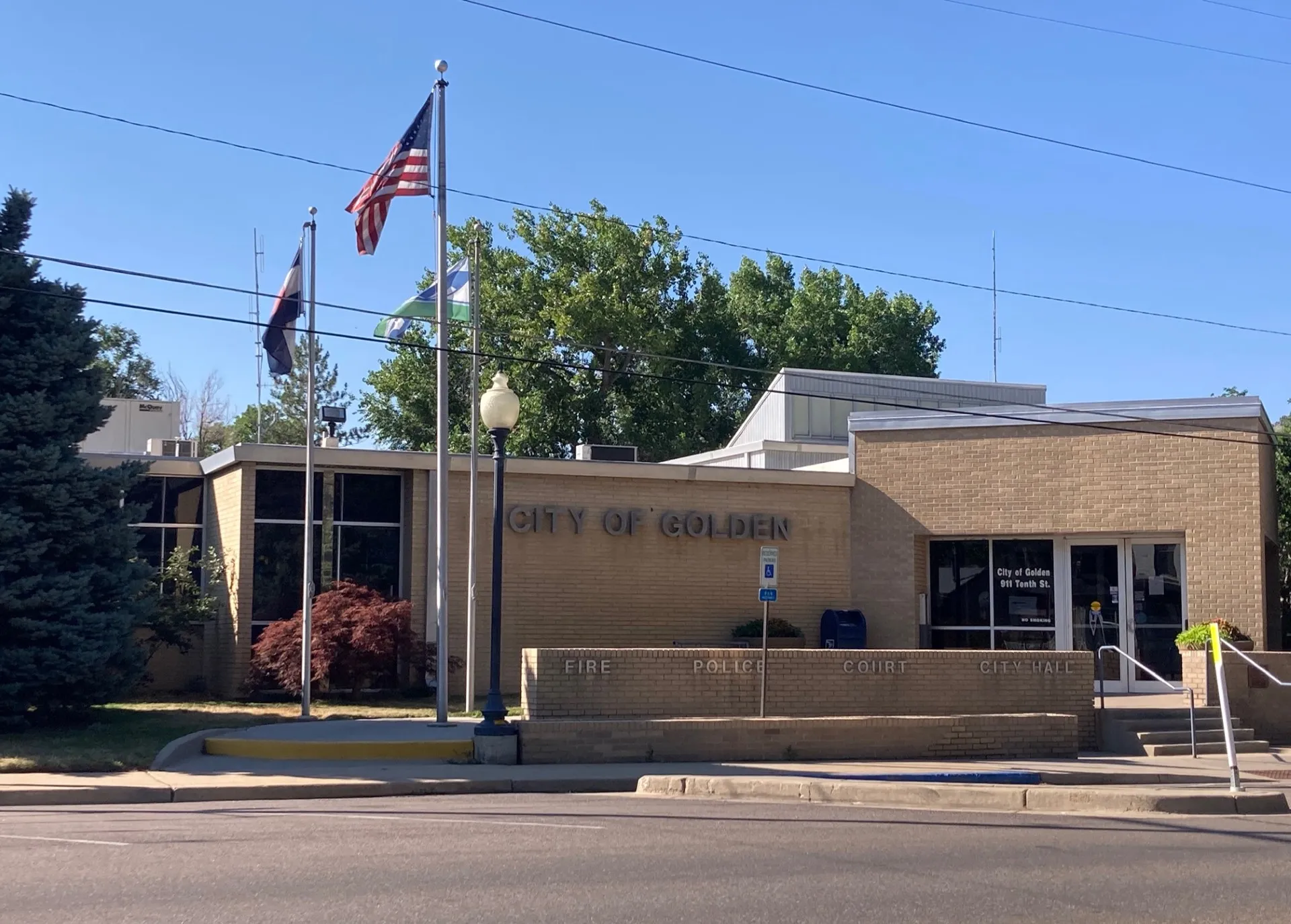 golden city hall - light tan brick building with 3 flags on pole in front