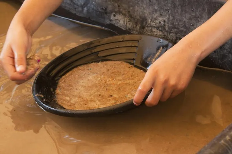 hands and a pan full of sand--panning for gold