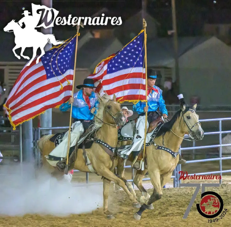 2 teenagers on horseback carrying American flags into an arena