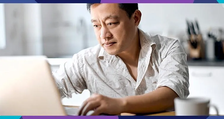 man working on laptop with a coffee cup next to him