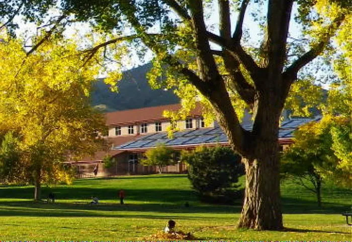 Golden Community Center in background - child playing in a pile of fall leaves in the foreground