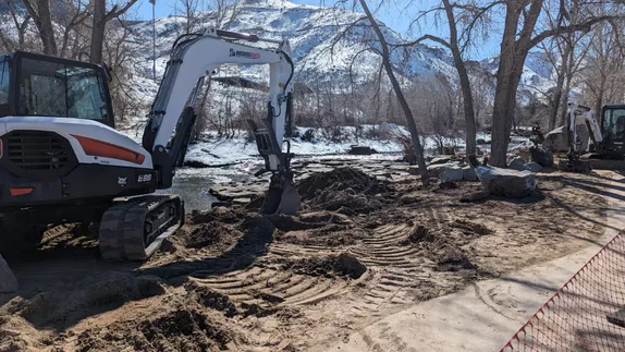 Heavy equipment digging up sand from the beach area along Clear Creek