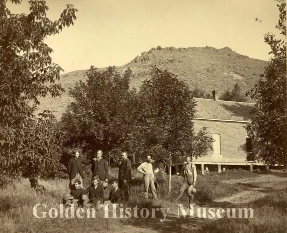 5 men and 3 boys in an orchard with North Table Mountain in the background