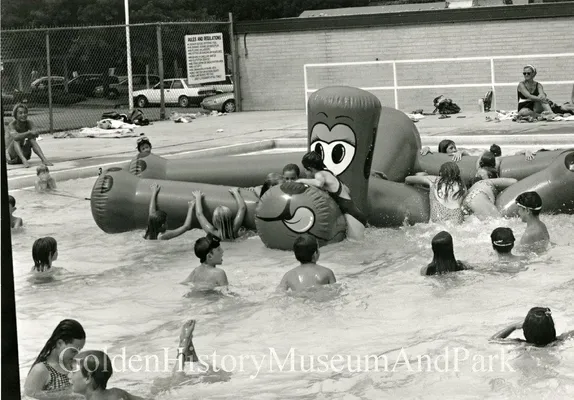 Children in a swimming pool playing with a large inflatable toy