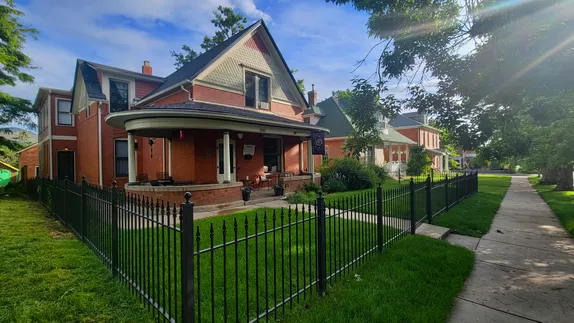 wrought iron fence around a brick house with front porch.  