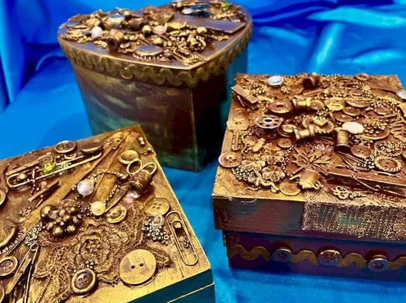 Golden-bronze-colored boxes with trinkets glued to the lid