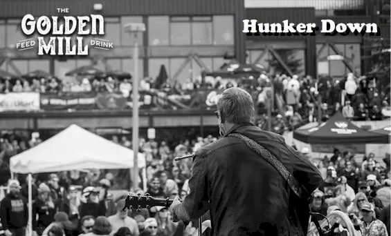 man with guitar, back to camera, facing a crowd