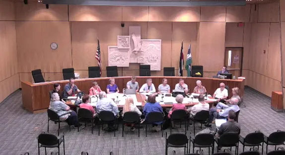 19 people city around a conference table in City Council chambers