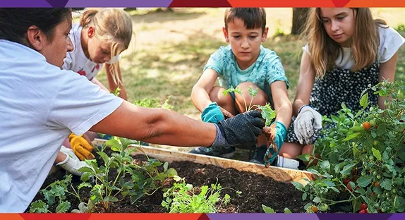 One adult and 3 children working in a garden