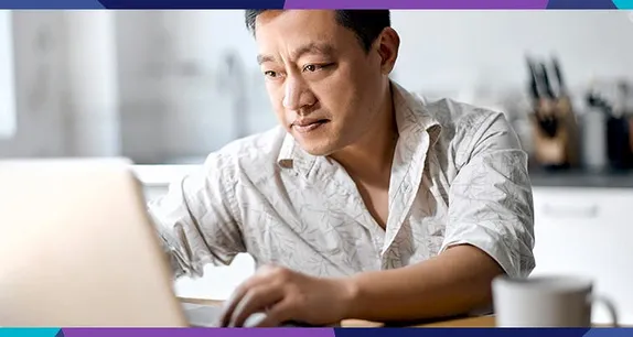 man working on laptop with a coffee cup next to him